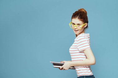 Mavi arka plan ve sarı gözlük modeli saç kesimi üzerine kitapları olan bir kız öğrenci.