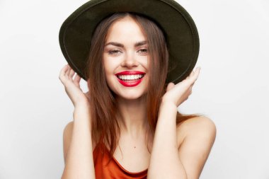 Şapkalı bir kadının portresi. Gülümseme, yüz modeline yakın eller. 