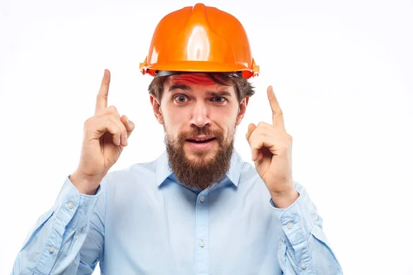 Um homem gesticula com as mãos um engenheiro laranja duro chapéu construção de segurança — Fotografia de Stock
