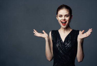 Gri arka plan fotokopisi olan çekici bir kadın el kol hareketi yapıyor.