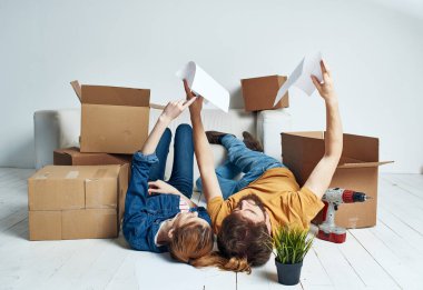 Saksıda çiçekli bir kadın, kanepenin yanındaki parlak bir odada yerde yatıyor.