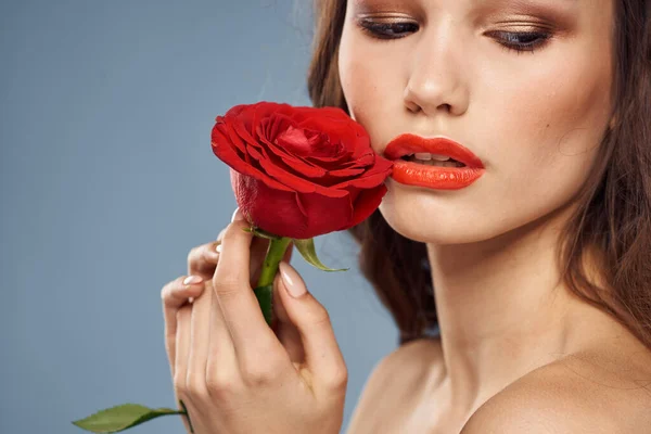 Donna con una rosa tra le mani spalle nude trucco sera labbra rosse — Foto Stock