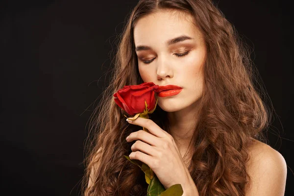 Donna con una rosa rossa su uno sfondo scuro trucco capelli lunghi labbra rosse — Foto Stock