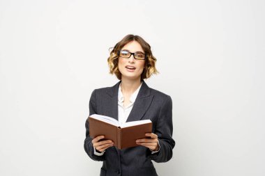 Not defteri ve gözlüklü bir iş kadını takım elbise modelinin hafif arka planında çalışıyor..