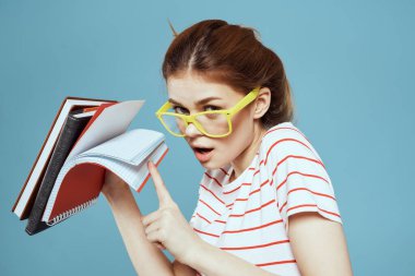 Not defterleri ve sarı gözlükleriyle mavi arka plan bilim enstitüsünde güzel bir bayan öğrenci.