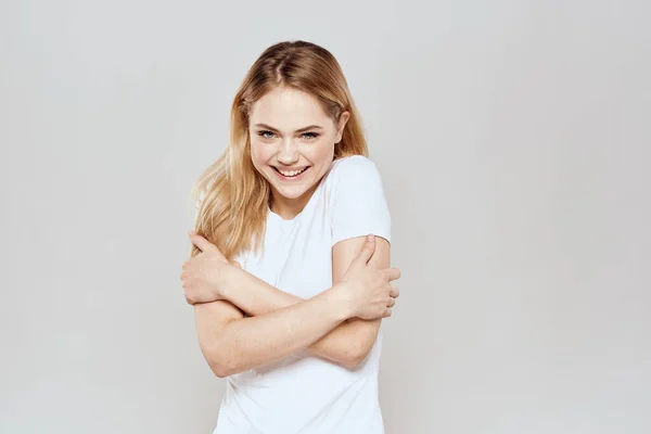 Lystig blondine i hvit T-skjorte med håndflatt lys bakgrunn – stockfoto