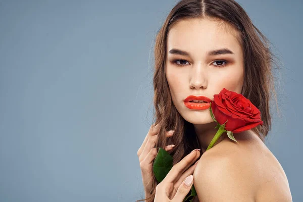 Donna con una rosa tra le mani spalle nude trucco sera labbra rosse — Foto Stock