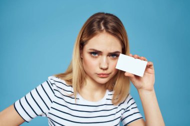 Elinde kartvizit olan bir kadın çizgili bir tişört mavi arka plan