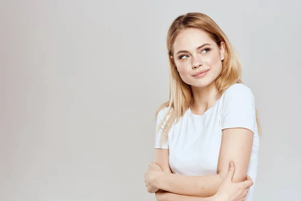 Söt blond vit t-shirt gest med händer livsstil ljus bakgrund — Stockfoto