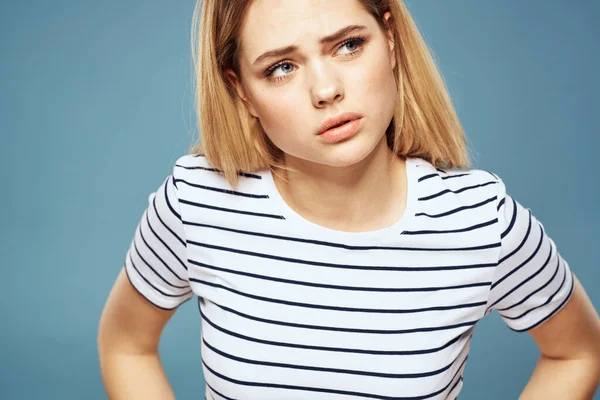 티셔츠 줄무늬 옷을 입은 한 여성이 푸른 색외진 배경을 보고 불쾌 한 표정을 짓고 있다 — 스톡 사진
