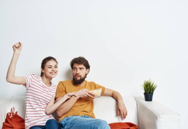 Güzel bir kadın ve sakallı bir adam kanepede televizyon izliyor.