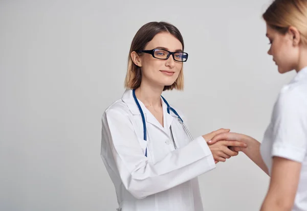 Professionele arts vrouw en patiënt handen schudden op een lichte achtergrond — Stockfoto