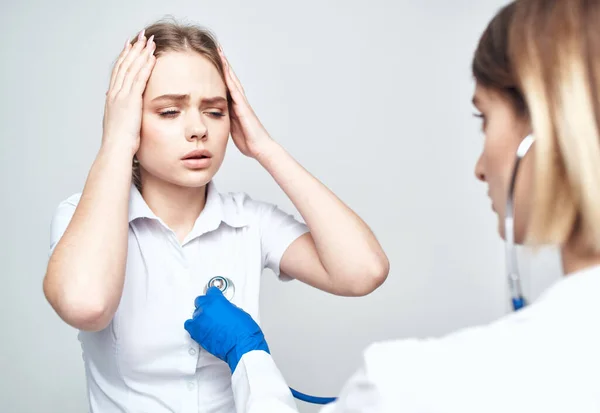 Woman patient complains of headache to doctor with stethoscope