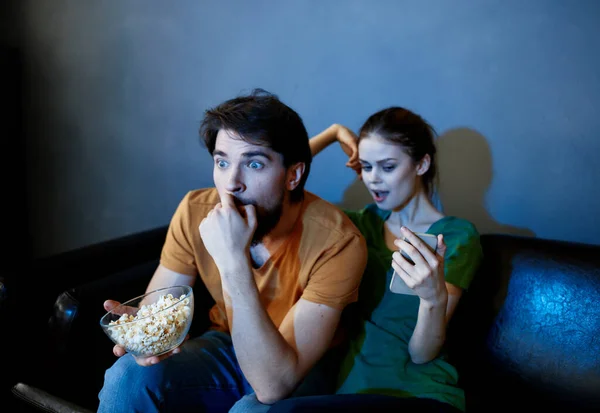 Freunde vor dem Fernseher auf der Couch und Popcorn im Teller — Stockfoto