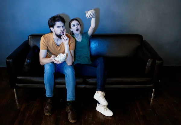 Un hombre y una mujer están viendo la televisión por la noche en el interior — Foto de Stock