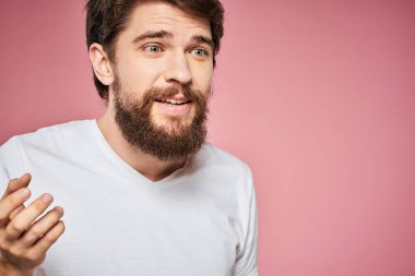 Beyaz tişörtlü adam duygu dolu yaşam tarzı yüz ifadesi pembe arkaplanı kırptı.