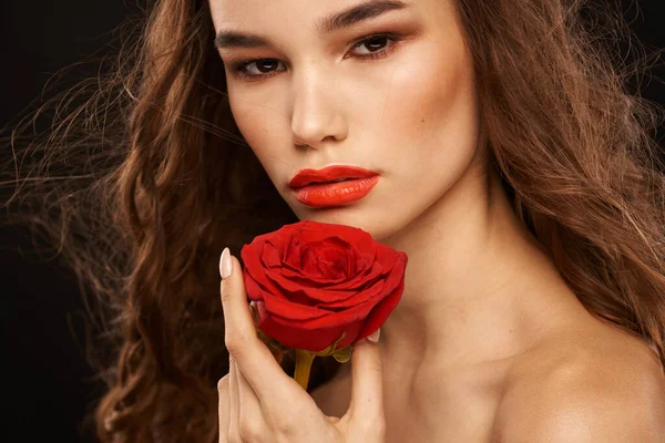 Femme avec une rose rouge sur un fond sombre cheveux longs maquillage lèvres rouges — Photo