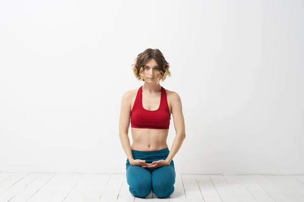 Kız yoga yapıyor, arka planda kırmızı tişörtlü, elleriyle el kol hareketi yapıyor. — Stok fotoğraf