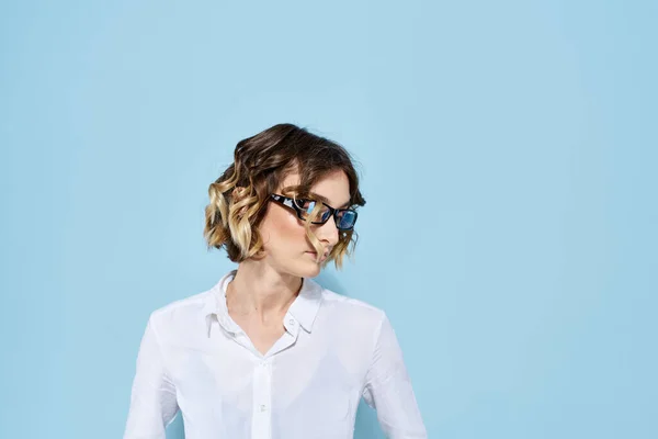 Mulher de negócios em um fundo azul óculos com jantes escuras cabelo encaracolado Camisa leve corte vista — Fotografia de Stock
