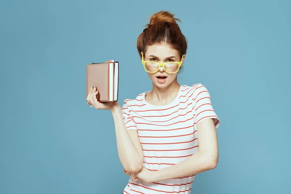 Female student with books in hands on a blue background and yellow glasses model hairstyle cropped view — Stock Photo, Image