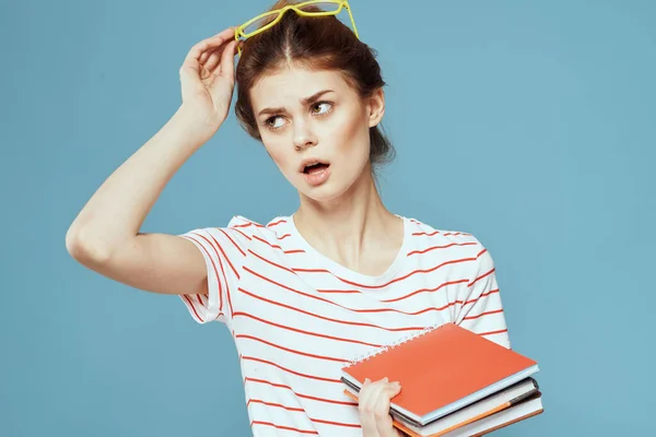 Mooie vrouwelijke student met notitieblokken en in gele bril op een blauwe achtergrond onderwijs wetenschappelijk instituut — Stockfoto