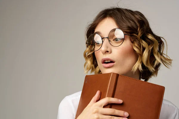 Vrouw met notitieblok in handen zakelijke werk beige achtergrond bril kapsel — Stockfoto