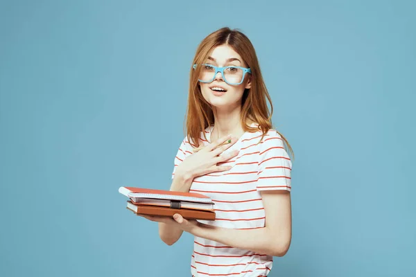 Girl in fashionable glasses with notebooks in hands on a blue background cropped view Copy Space — Stock Photo, Image