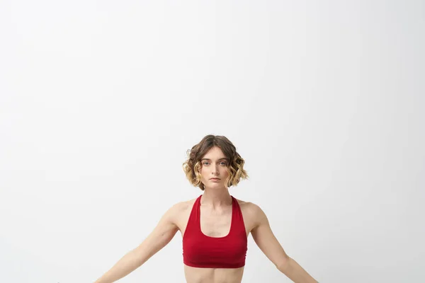 La ragazza è impegnata in yoga su uno sfondo chiaro T-shirt rossa gesticolando con le mani — Foto Stock