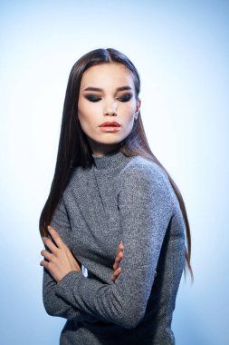 Çekici, parlak makyajlı bir kadın zarif bir modelle saçlarını düzleştiriyor.