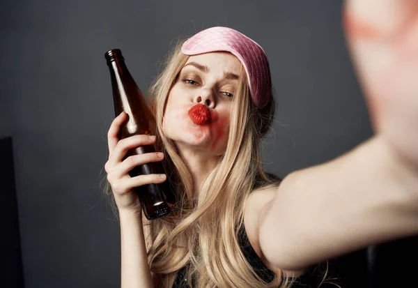 Femme ivre avec une bouteille de bière sur un fond gris gestes avec ses mains et maquillage lumineux — Photo