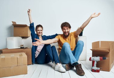 Yerde karton kutuları olan duygusal erkek ve kadın tadilat işinde eğleniyorlar.