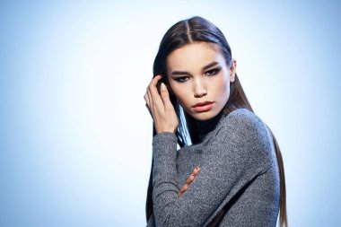 Çekici, parlak makyajlı bir kadın zarif bir modelle saçlarını düzleştiriyor.