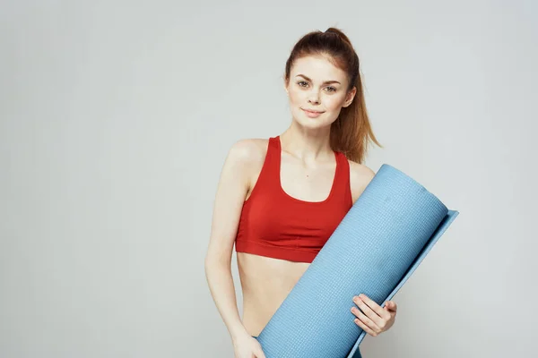 Mulher segura na mão um tapete para fitness esporte figura slim exercícios fundo leve — Fotografia de Stock