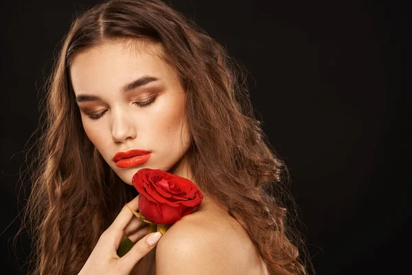 Femme avec une rose rouge sur un fond sombre cheveux longs maquillage lèvres rouges — Photo