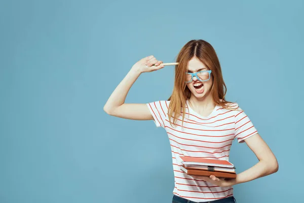 Девушка в модных очках с ноутбуками в руках на синем фоне обрезанный вид — стоковое фото