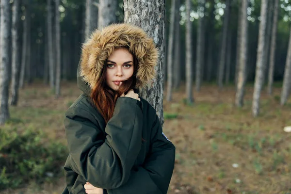 Mulher com um capuz na cabeça perto de uma árvore no fundo de uma viagem de floresta de outono — Fotografia de Stock
