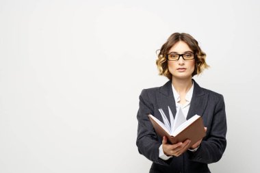 Klasik takım elbiseli bir iş kadını elinde bir not defteri ve yüzünde gözlüklerle.
