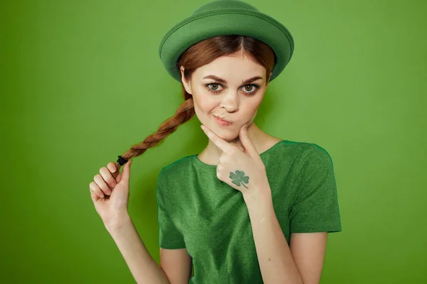 녹색 배경 휴일에 손에 샴록을 들고 있는 예쁜 소녀 세인트 Patricks Day fun hat on her head. — 스톡 사진