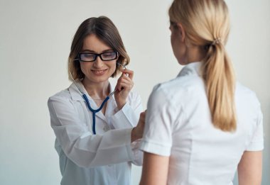 Doktor, hastaların kalp atışlarını steteskopla dinler.