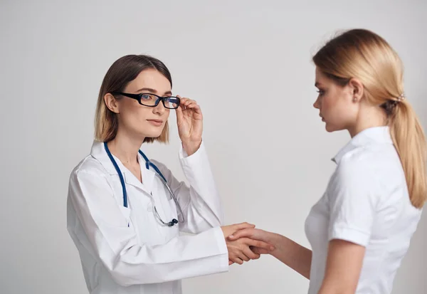 Профессиональная женщина-врач и пациент пожимают руку на светлом фоне — стоковое фото