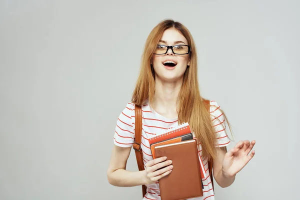 Étudiante avec bloc-notes et lunettes sur un fond clair vue recadrée d'un T-shirt rayé — Photo