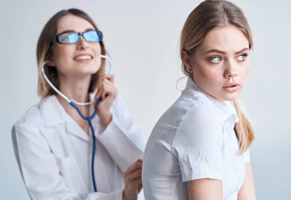 Счастливая женщина врач осмотреть пациентку в белой футболке модели здоровья — стоковое фото