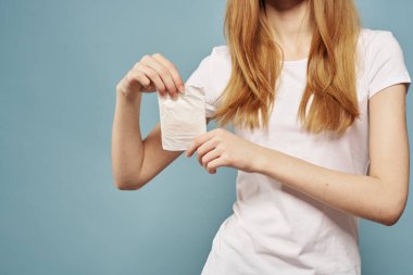 Mavi arka planda yastıklı bir kız. Adet günleri, hijyenik görünüm.
