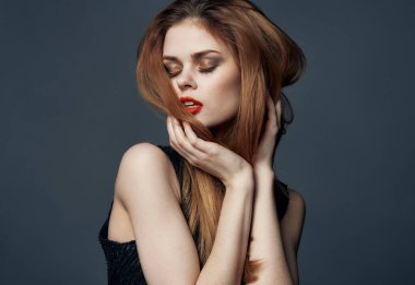 Kızıl saçlı, siyah elbiseli, kırmızı dudaklı ve göz farlı bir kadın.