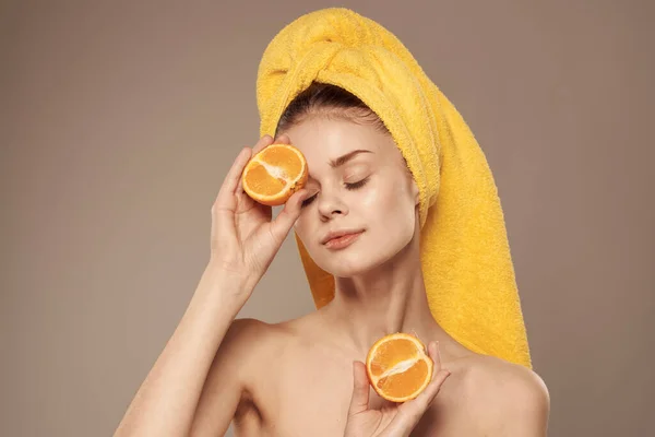 cheerful woman holding oranges near her eyes skin care