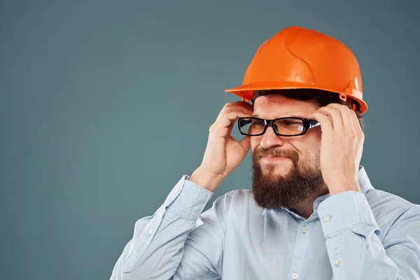 Homem barbudo em tinta laranja e óculos de construção trabalho fundo azul — Fotografia de Stock