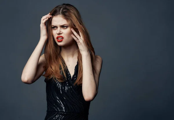 Dame aux cheveux rouges dans une robe noire aux lèvres rouges gestes avec ses mains, vue de face — Photo