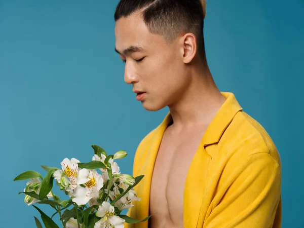 裸の胴に黄色のコートを着たロマンチックな男と花の花束と彼の手で休日を保持 — ストック写真