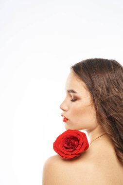 Kırmızı gül ve çıplak omuzlu esmer yüzlü kadın portresi.