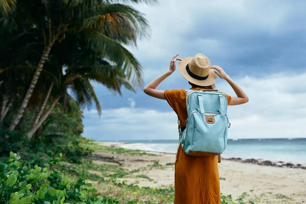 En resenär i solklänning med en ryggsäck på en ö nära havet. — Stockfoto